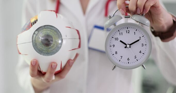 Ophthalmologist holds eye anatomy and alarm clock