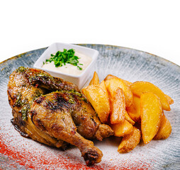 Roasted chicken with golden potatoes and white sauce on a plate