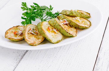Grilled zucchini slices with herbs and spices on white plate