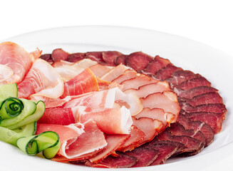 Plate presenting delicious cured meat slices with cucumber decoration