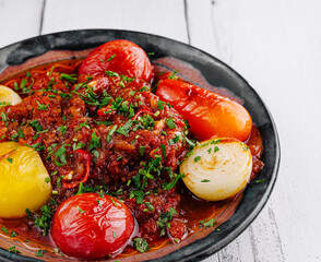 Spicy beef stew garnished with fresh herbs and vegetables on rustic plate