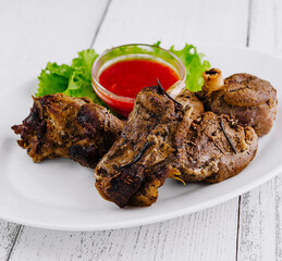 Roasted lamb shanks with rosemary and red spicy sauce on white plate