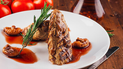 Grilled meat with figs and rosemary lying on a white plate
