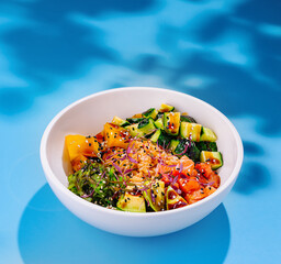White bowl presenting colorful hawaiian style poke bowl with salmon and mango