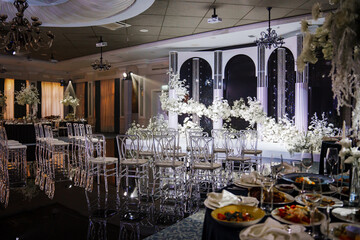Banquet hall decor for a wedding. White flowers, mirrors and lighting. table setting and services...