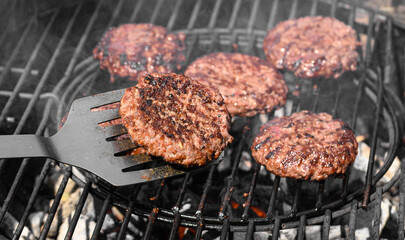 Piękne soczyste burgery wołowo-wieprzowe grillowane nad rozżarzonym węglem drzewnym na ruszcie 