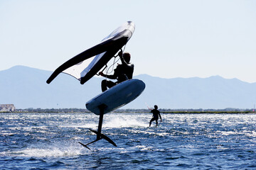 Man practising windfoil jumping at the beach.