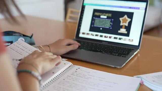 Girl studies and does homework at her desk at home, with book, notes and laptop on which she made a presentation