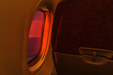 A close-up view of an economy class window seat in an airplane - Sunset Glow Through the Glass