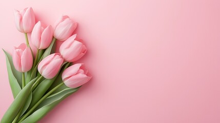A bouquet of pink tulips is arranged on a pink background. The flowers are the main focus of the image, and they create a sense of beauty and elegance. The pink background adds a touch of softness