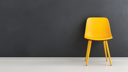 A yellow chair is sitting in front of a black wall. The chair is empty and the wall is bare