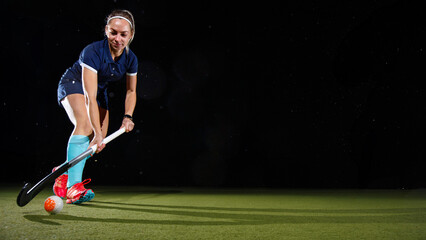 Determined young woman skillfully leading the ball with the field hockey stick focused on her game.