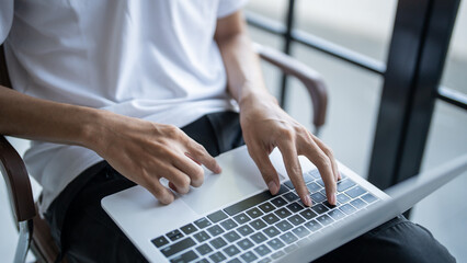 The man is focused on his laptop screen typing work or a task at hand..