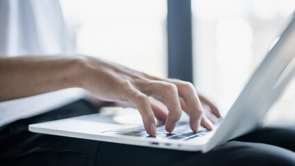 The man is focused on his laptop screen typing work or a task at hand..