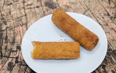 fried rolls on white plate, wooden table 
