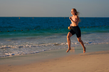 Sporty woman running at the beach. Girl runner runs by the sea during sunset. Young woman running on sunrise beach. Sport is healthy! Train whenever you can.