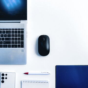 top view of office stationery and equipment: laptop, smartphone, mouse, folder, pen on a white background and copy space on the top right corner