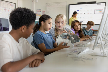 Two girl students in science class looking at a VR headset together