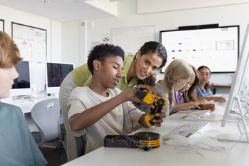 Computer science teacher looking at students robotic arm project