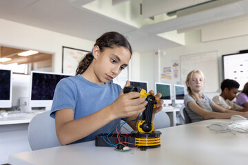 Hispanic school girl working on a robotic arm in class