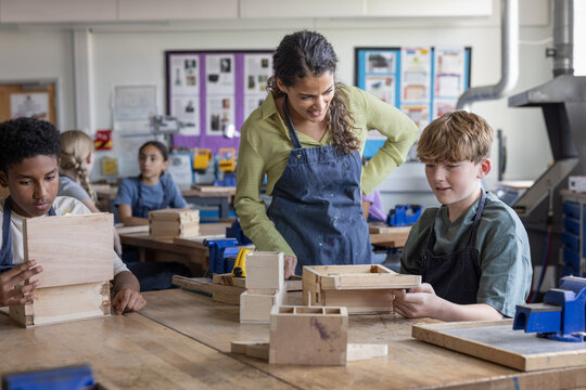 Boy student showing teacher his project in woodworking class - Powered by Adobe