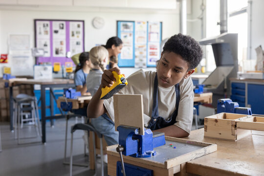 African American boy learning carpentry in woodworking class at school