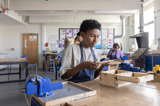 African American boy learning carpentry in woodworking class at school