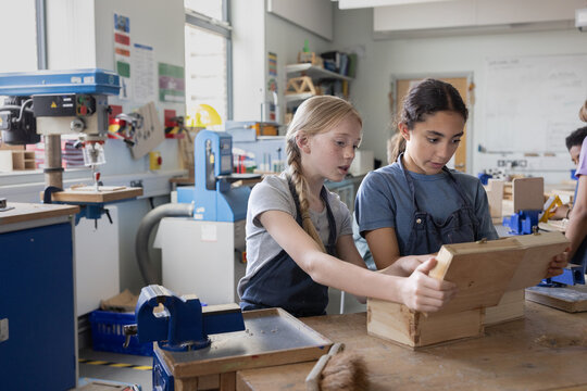 Two girl students looking at their projects in woodworking class