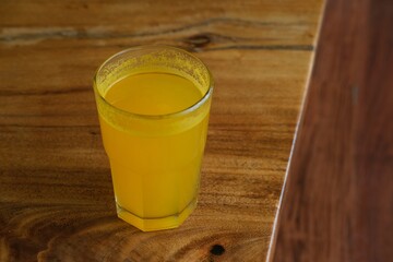  refreshing glass of warm orange juice on a wooden table with a natural background. Ideal for use...