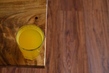  refreshing glass of warm orange juice on a wooden table with a natural background. Ideal for use...