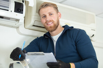 Fototapeta premium professional technician maintaining air conditioner indoors