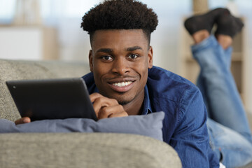 man holding a tablet laying on the sofa