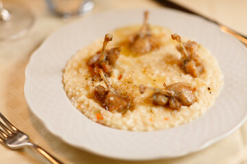 Close up on italian traditional northern food on a restaurant table. Risotto with frogs legs.