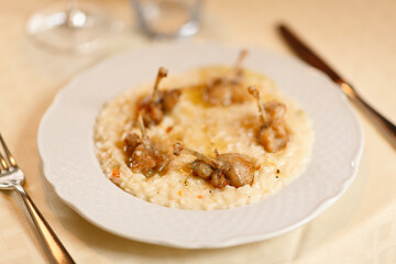 Close up on italian traditional northern food on a restaurant table. Risotto with frogs legs.