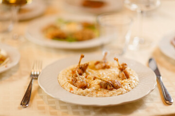 Close up on italian traditional northern food on a restaurant table. Risotto with frogs legs.