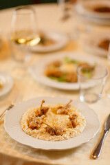 Close up on italian traditional northern food on a restaurant table. Risotto with frogs legs.