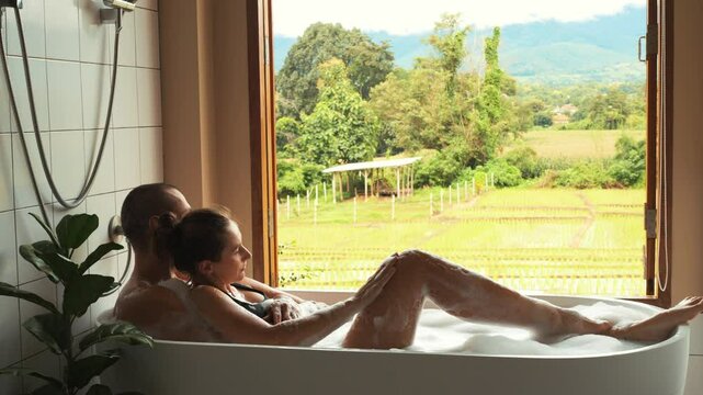 Romantic Bath: Couple Relaxing Together in a Bathtub, Woman Leaning Back on Her Partner, Overlooking Scenic Rice Fields in Thailand, Honeymoon Serenity and Intimacy