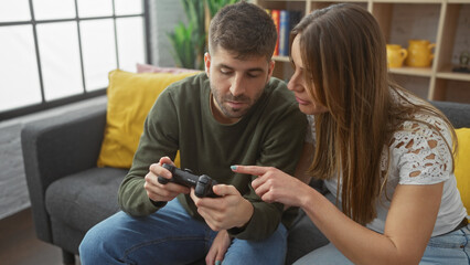 A woman guides a man playing video games in a cozy living room, reflecting a candid moment of leisure and bonding.