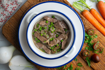 Strips of beef cooked with onion and peas. Top view table with  decoration.