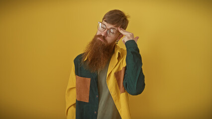 Pensive redhead man with beard contemplating isolated over yellow background