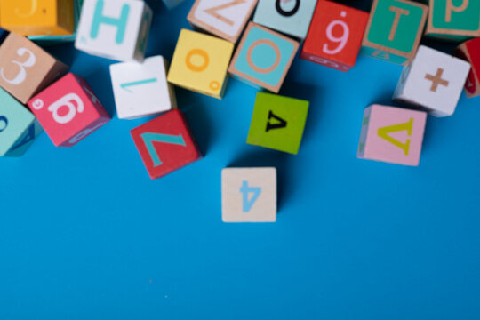 Colorful alphabet blocks scattered on a bright blue background Learning is fun