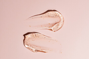 Golden flecks in luxury cream gel smears on pale background