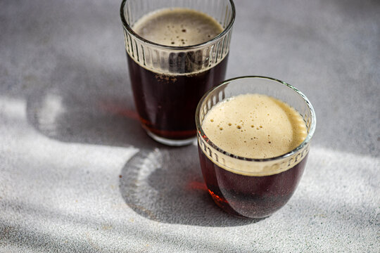 Two Glasses of Kvass Drink on a Light Surface with Shadows