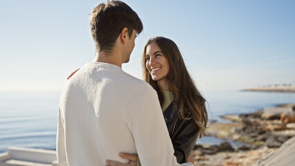 Obraz premium A loving couple enjoying a sunny day at the seaside, showcasing a candid moment of happiness and connection.