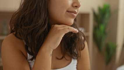 A beautiful young hispanic woman relaxes indoors at a spa, showcasing her attractive brunette...