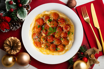 Savory tarte tatin with cherry tomatoes. Top view table with christmas decoration.