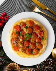 Savory tarte tatin with cherry tomatoes. Top view table with christmas decoration.