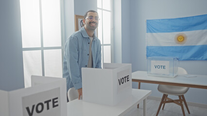 Young man casting vote in an argentinian electoral college room with a flag in the background and...