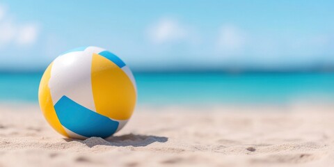 Beach ball on sand with blur sea, bright sunny day