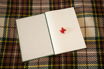 Notebook sewn with Coptic stitch on checkered blanket. Amateur bookbinding. First page and front cover.